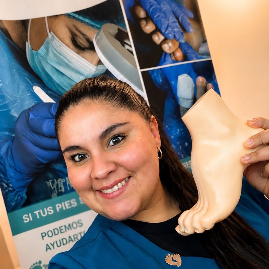 Carolina Cepeda, podóloga clínica, sonriendo en su consulta con un modelo anatómico de pie